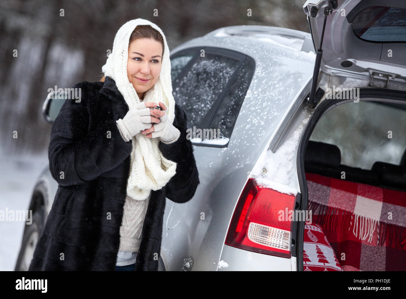 Mujer congelada en invierno ropa bebe té caliente mientras está parado  atrás del coche con la cajuela abierta Fotografía de stock - Alamy