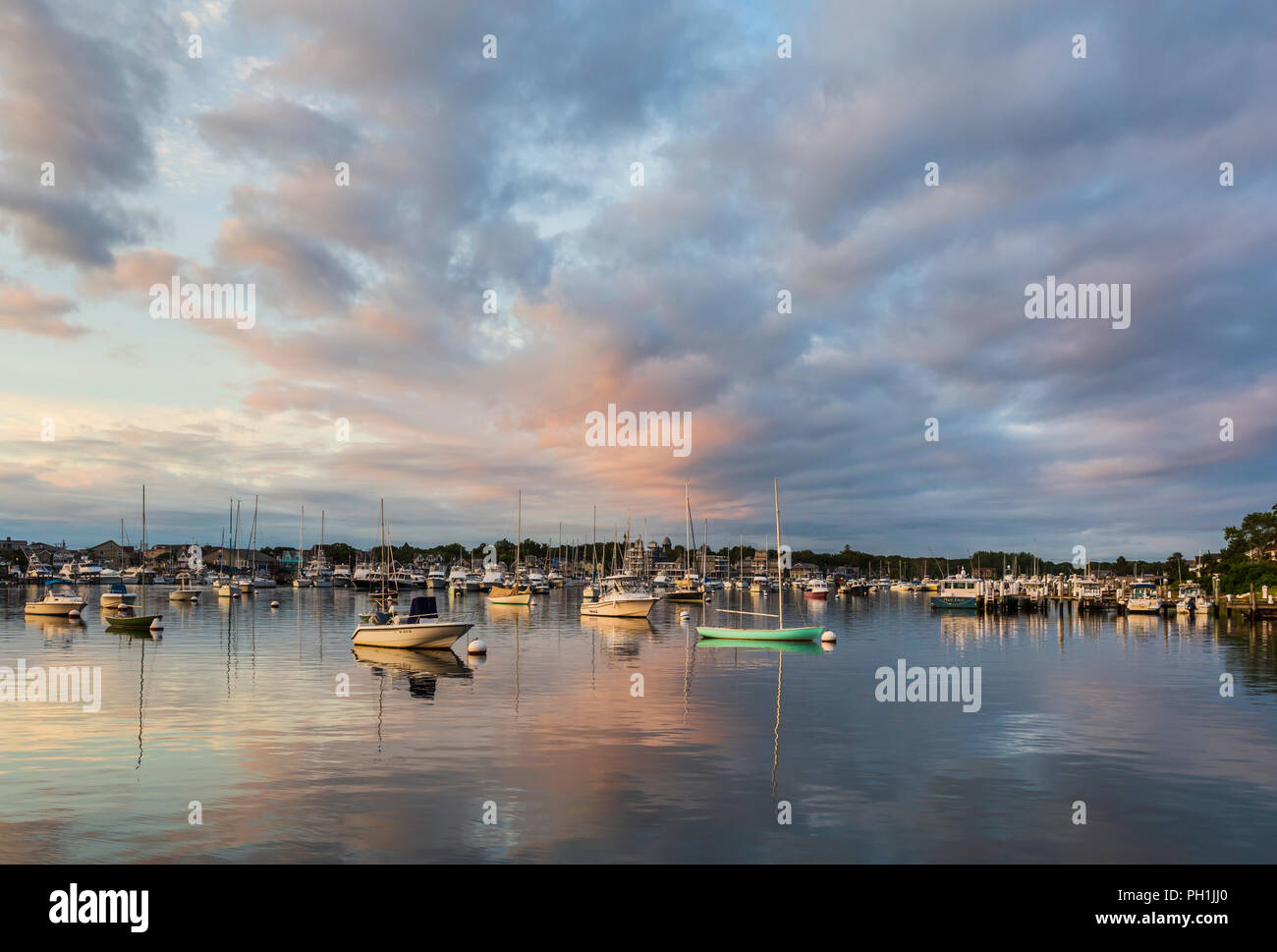 El sol naciente le añade color a la dramática nubes más soleada de barcos en el puerto justo después del amanecer en Oak Bluffs, Massachusetts en Martha's Vineyard. Foto de stock