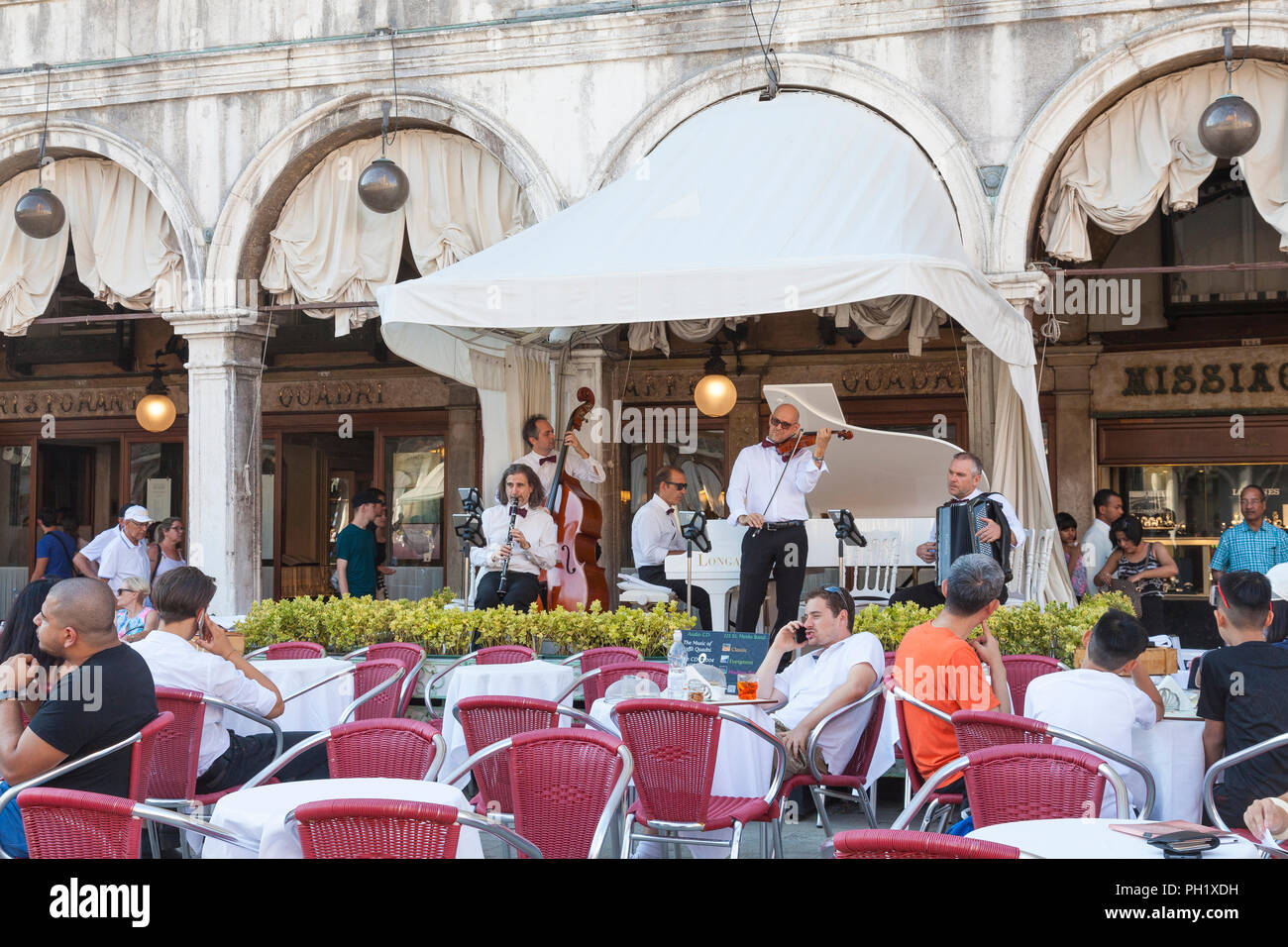 Música en directo en el Caffe Ristorante Quadri, Piazza San Marco, Venecia, Véneto, Italia con los turistas sentados en mesas al aire libre enkoying la sombra Foto de stock