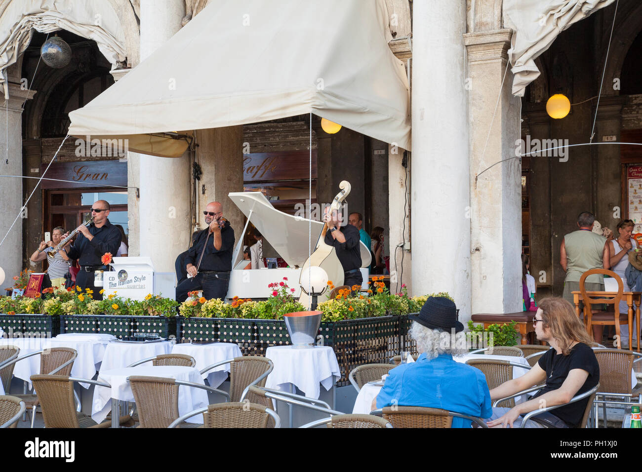 Las personas que escuchan música clásica en Gran Caffe Chioggia, Piazza San Marco, Venecia, Véneto, Italia mientras disfruta de las bebidas. La actuación en directo del italiano Foto de stock