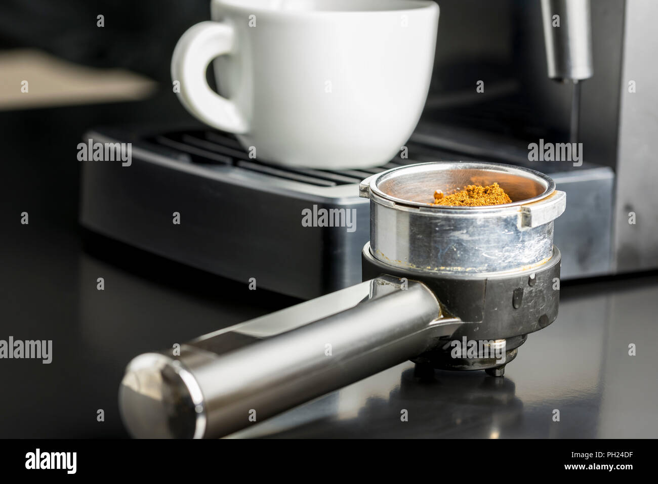 Preparar una taza de café espresso con una vista de cerca de los granos de  café recién molido en la medida de metal de una máquina de café con vistas  a la