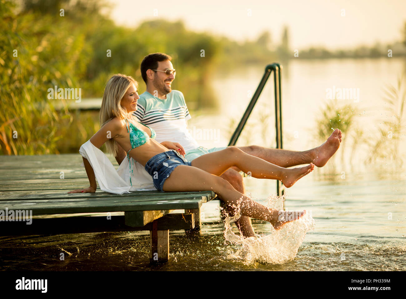 Pareja romántica sentado en el muelle de madera en el lago día soleado Foto de stock