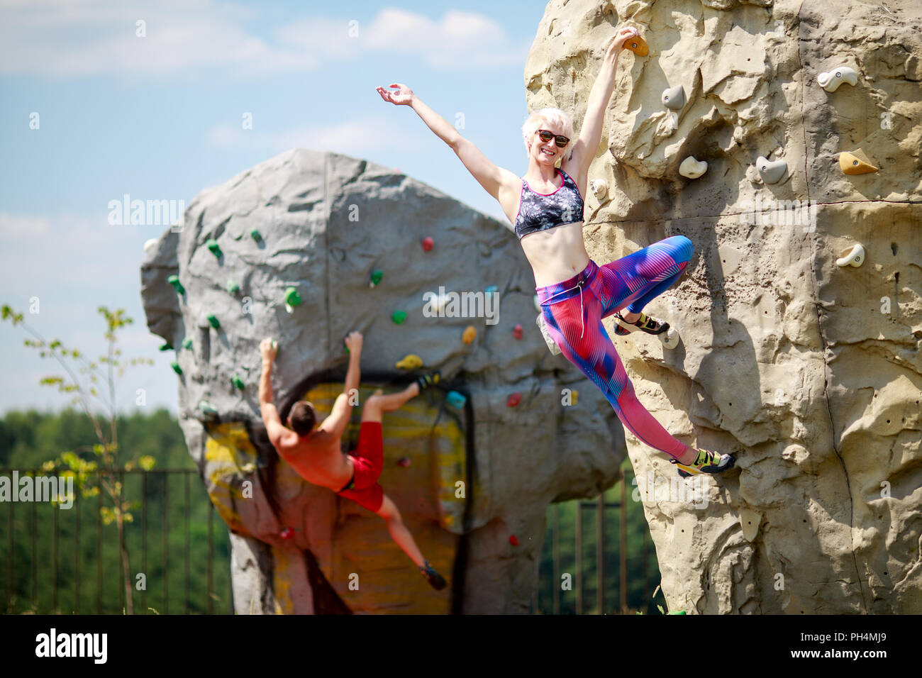 Foto de deportes hombre y mujer sonriente en gafas de sol de Foto de mujer sonriente escalador con gafas de sol sentado