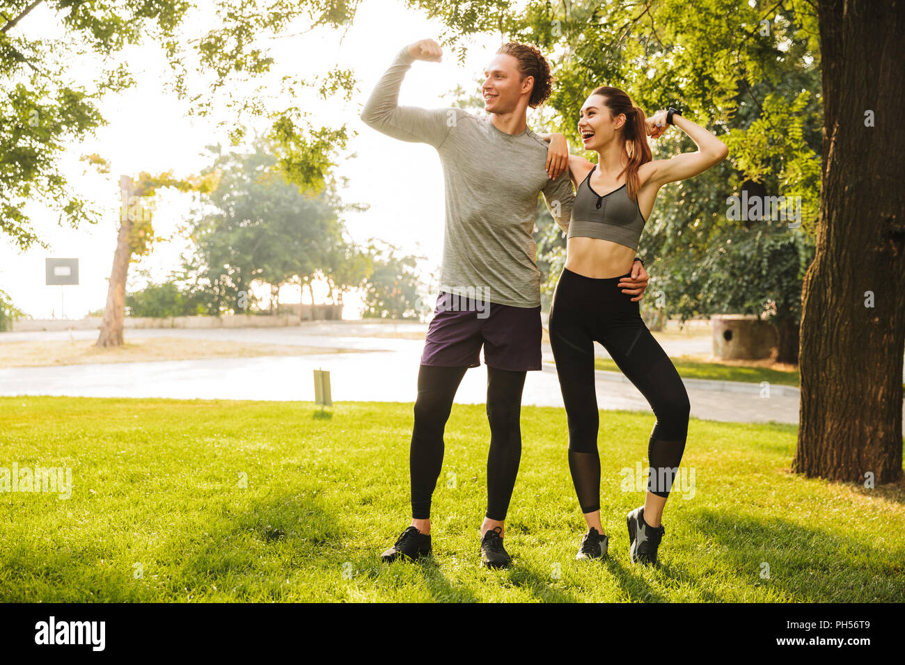 Foto de alegre gente deportiva hombre y mujer 20s en ropa deportiva  entrenamiento juntos y mostrando bíceps en Green Park durante un día  soleado de verano Fotografía de stock - Alamy