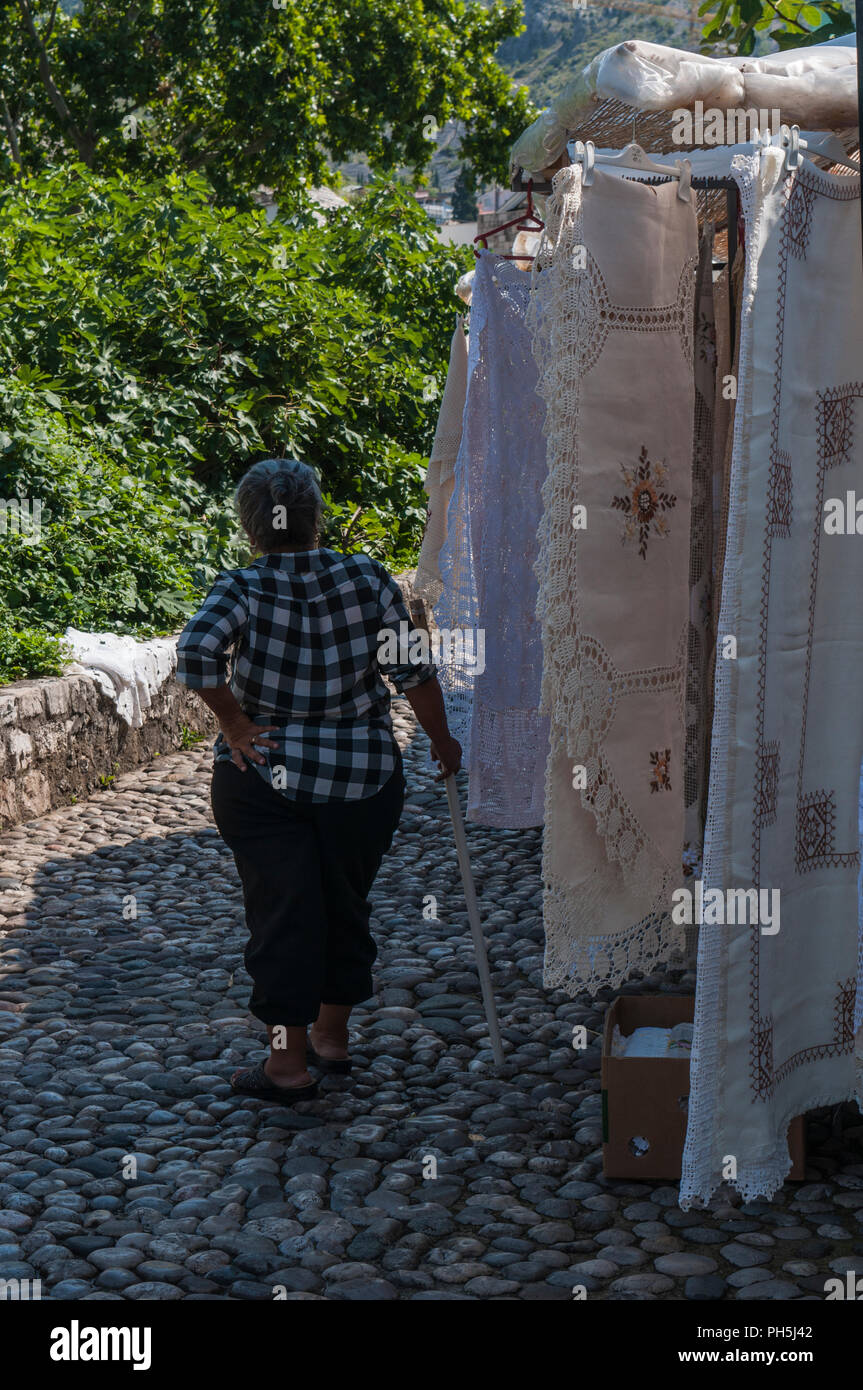Bosnia: un bosnio anciana vendiendo finamente tejidos bordados y encajes, creada según la antigua tradición de los Balcanes en los callejones de Mostar Foto de stock