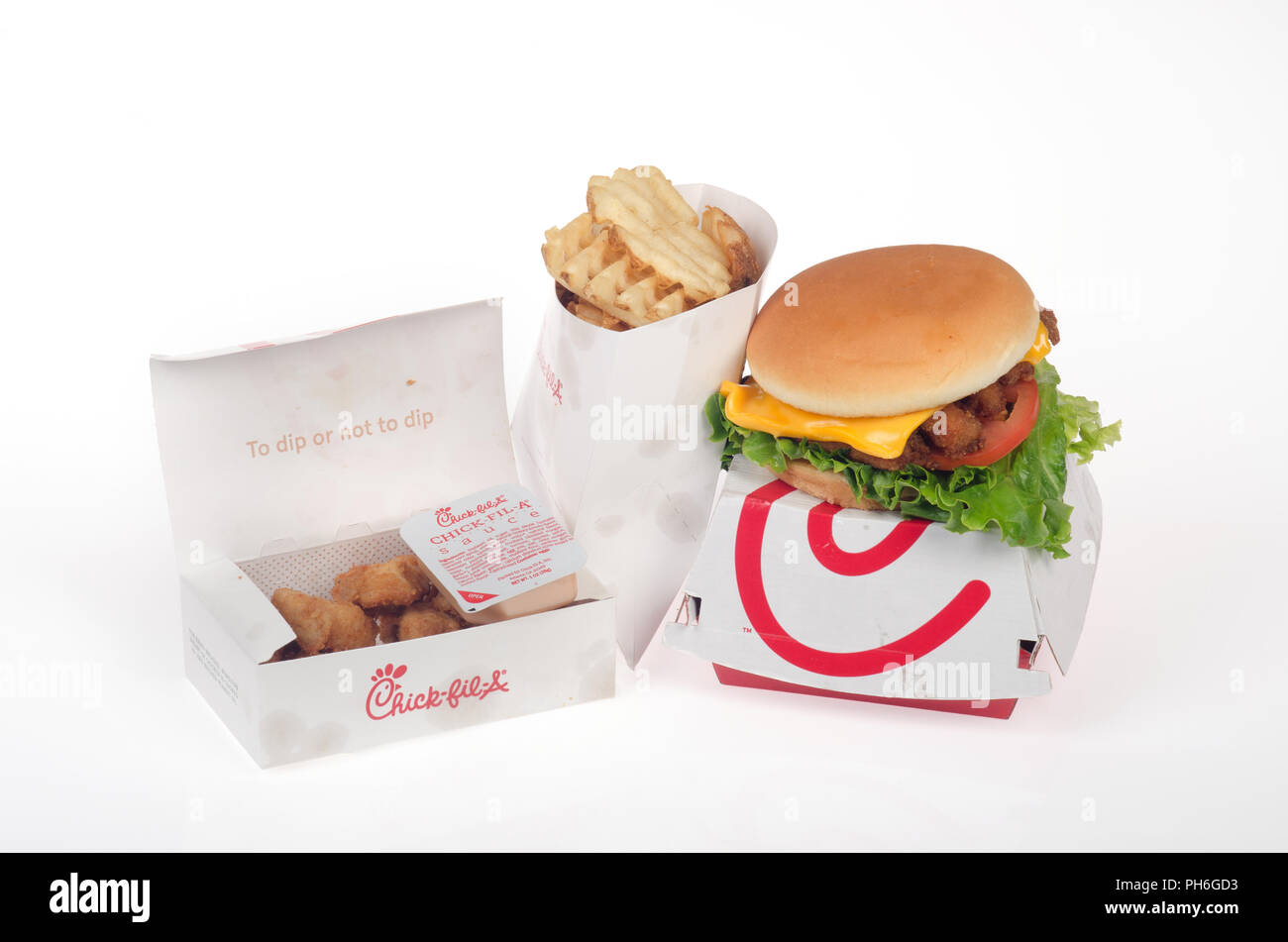 Chick-Fil-Deluxe un bocadillo de pollo con lechuga, tomate y queso en un panecillo encima de la caja con el gofre, patatas fritas y nuggets de pollo con salsa de soya dulce Foto de stock