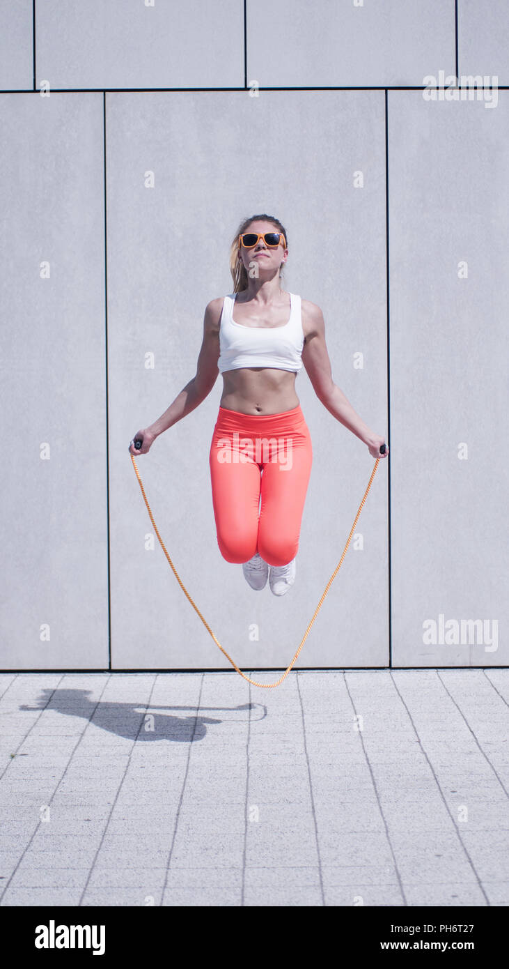 Energética mujer joven ejerciendo con saltar la cuerda Foto de stock