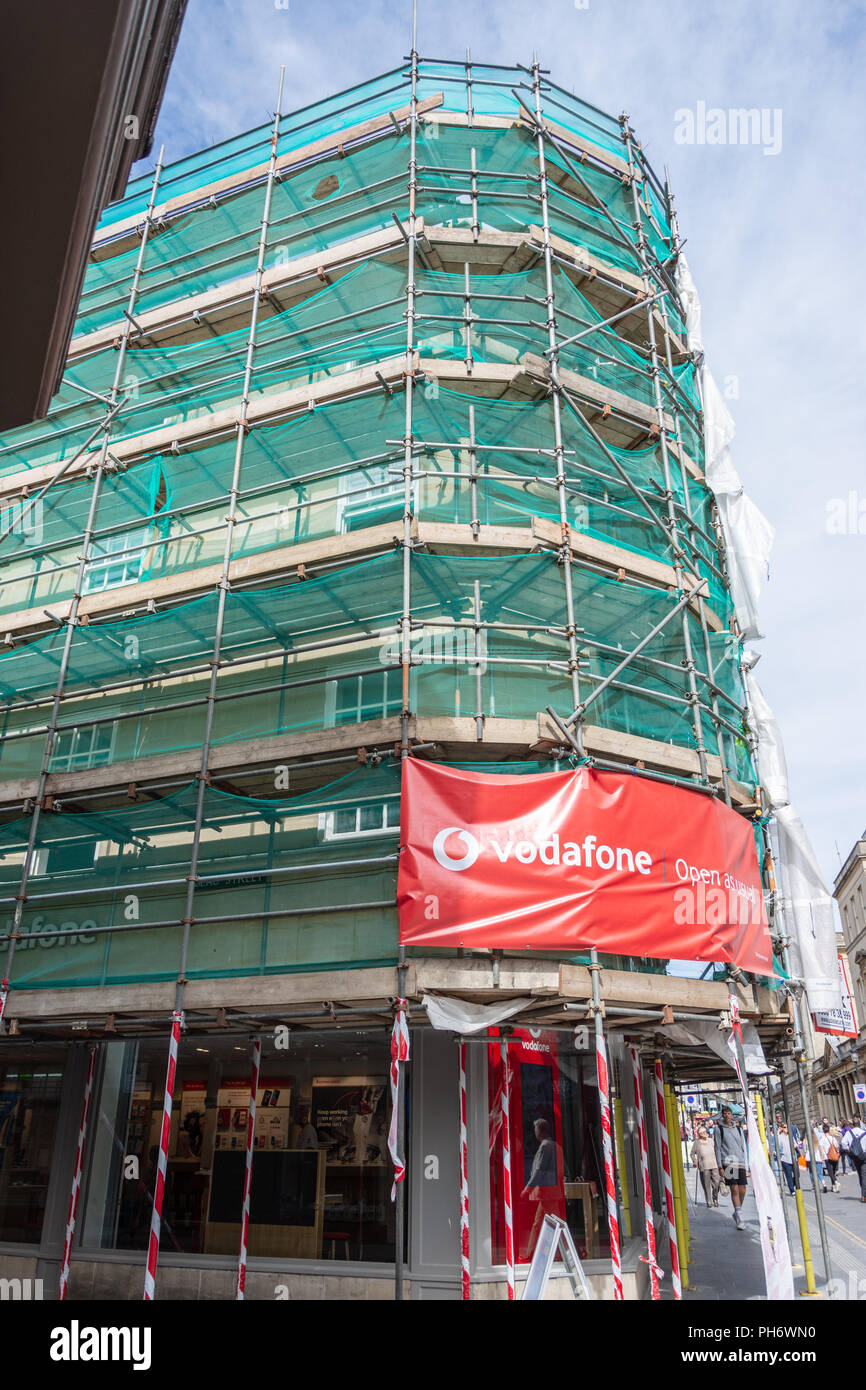 La puerta y la ventana de la tienda Vodafone en Bath con el edificio rodeado de andamios y compensación de color verde y un gran abiertos como es habitual firmar Foto de stock