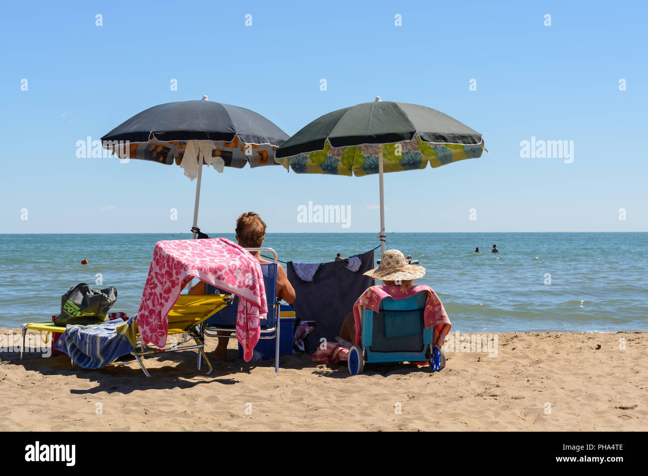 Dos bañistas que disfrutan de la playa de arena bajo el paraguas Foto de stock