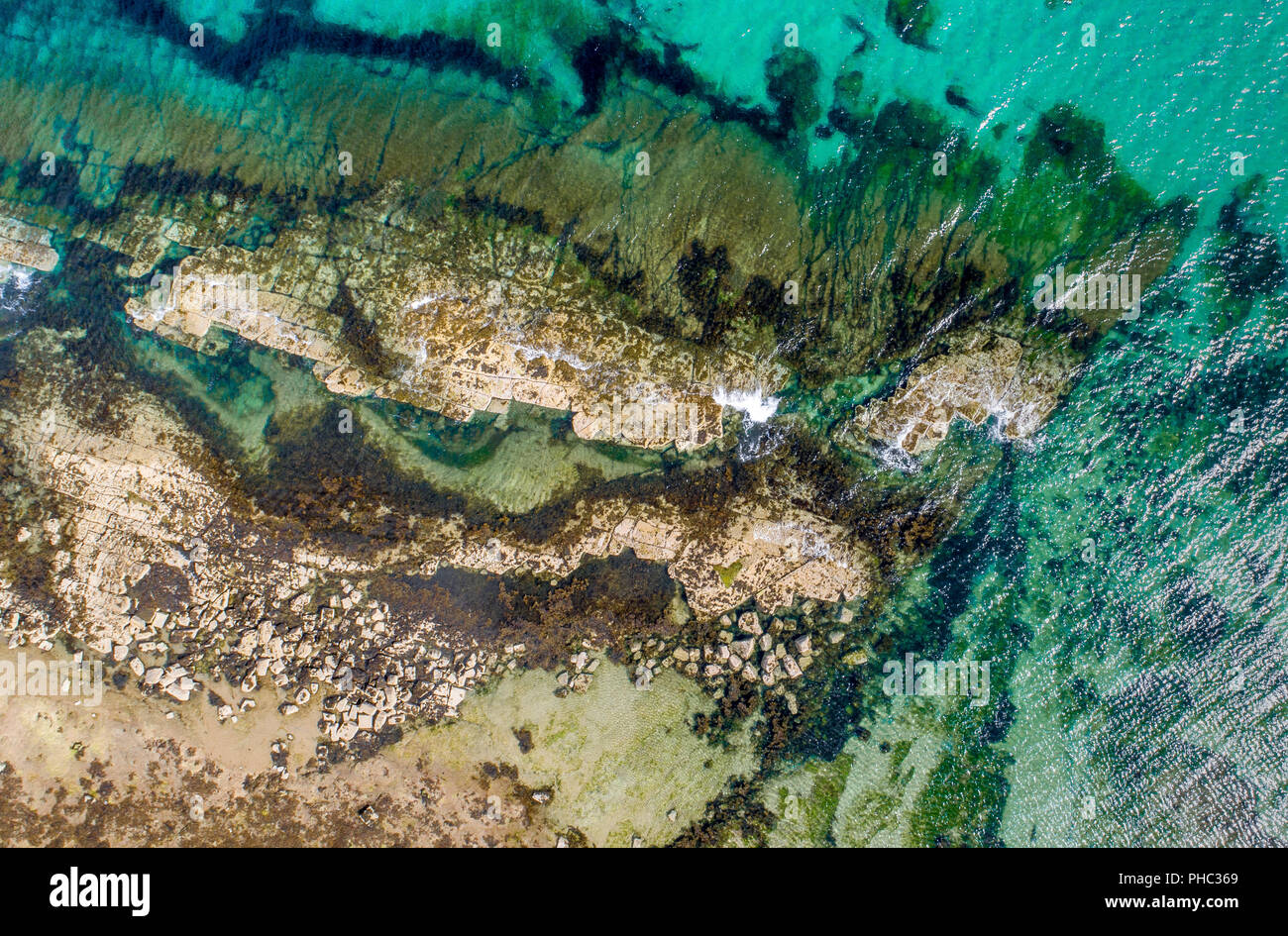 Una foto aérea de una playa con arena, rocas y el mar turquesa de las ondas acuáticas Foto de stock