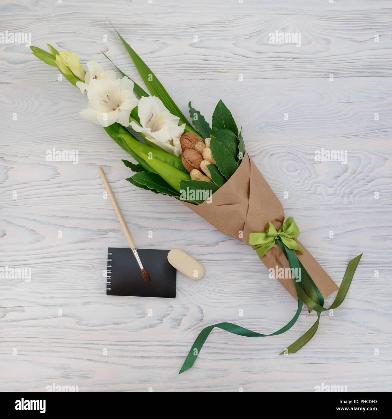 Pequeña y modesta bouquet compuesto de gladiolo, tuercas, papelería sobre una tabla de madera blanca como un regalo para el niño al comienzo de la escuela ye Foto de stock