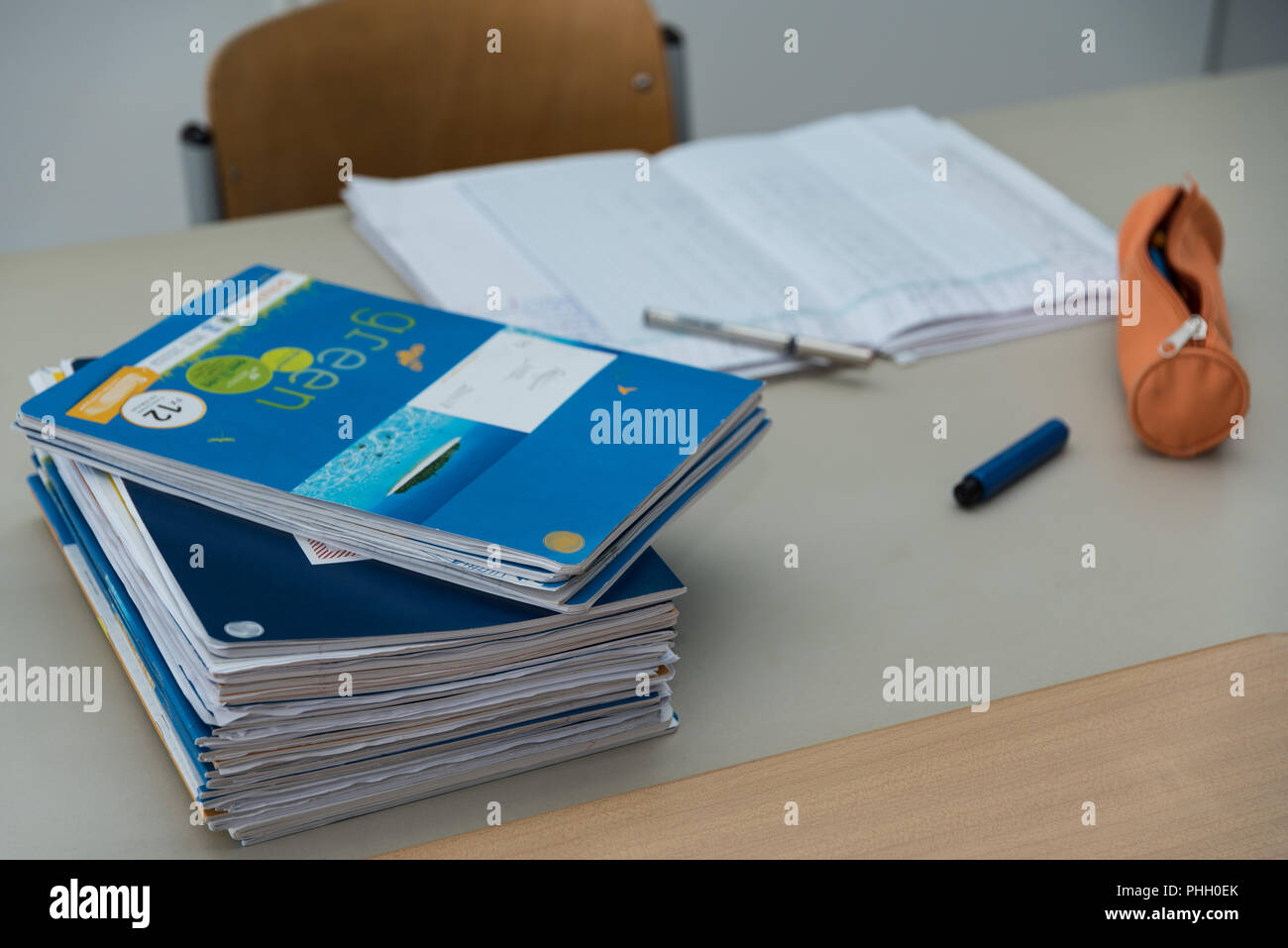 Pila de trabajo escolar en el Teacher's desk mientras corrige Foto de stock