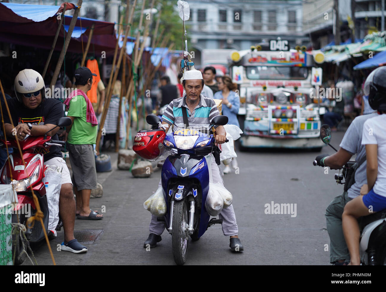 Un musulmán motociclista paseos a través de una concurrida calle dentro del mercado de carbono,en la Ciudad de Cebu, Filipinas Foto de stock