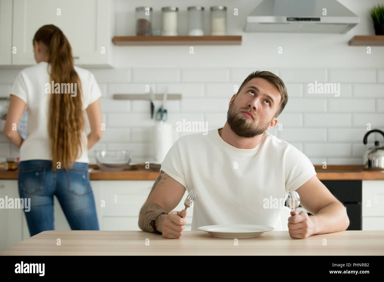 Perezoso marido aburrido en la cocina mientras espera para el desayuno Foto de stock