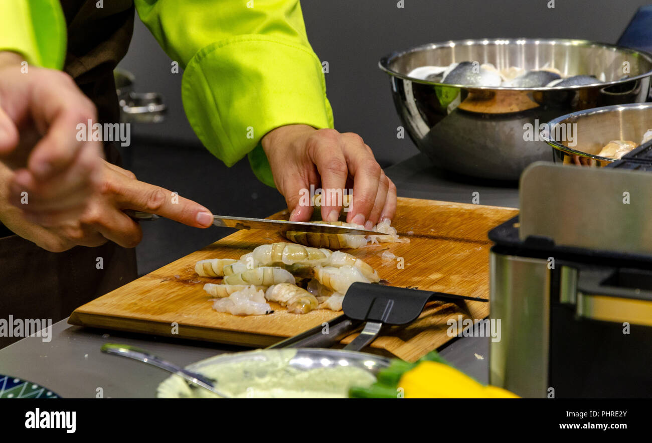 Cook expertamente pelando camarones bevore cocinar. Chef cortando los langostinos. Foto de stock