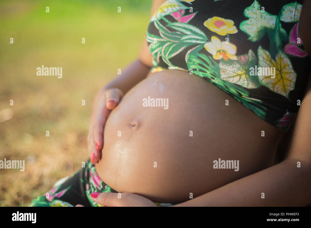 La mujer embarazada en un parque poner crema en su vientre para evitar las estrías. Foto de stock