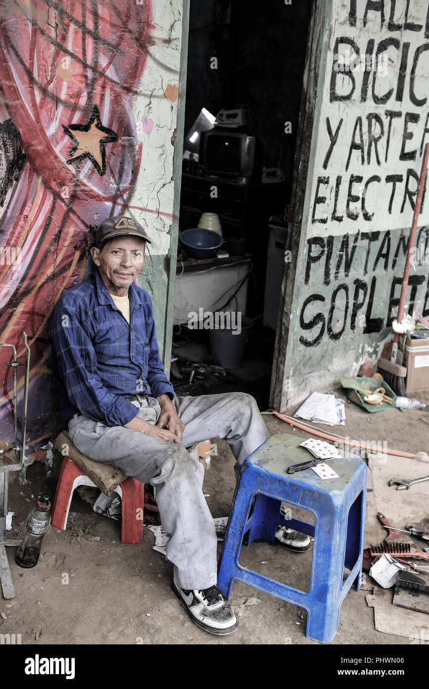 Retrato de un hombre sentado fuera de su taller de electrodomésticos en Manta, Ecuador Foto de stock