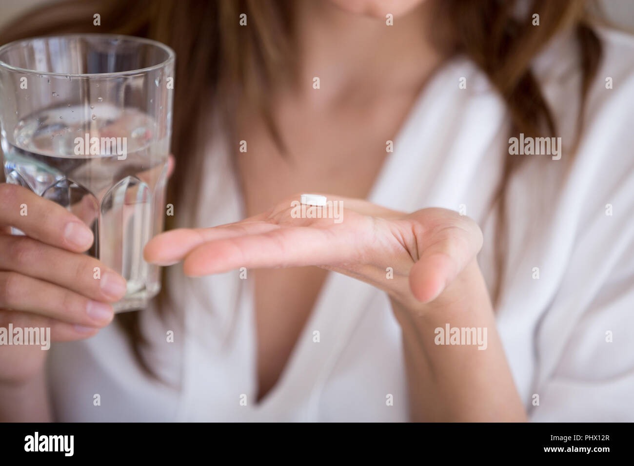 Mujer sosteniendo la píldora y vaso de agua, Vista cercana Foto de stock