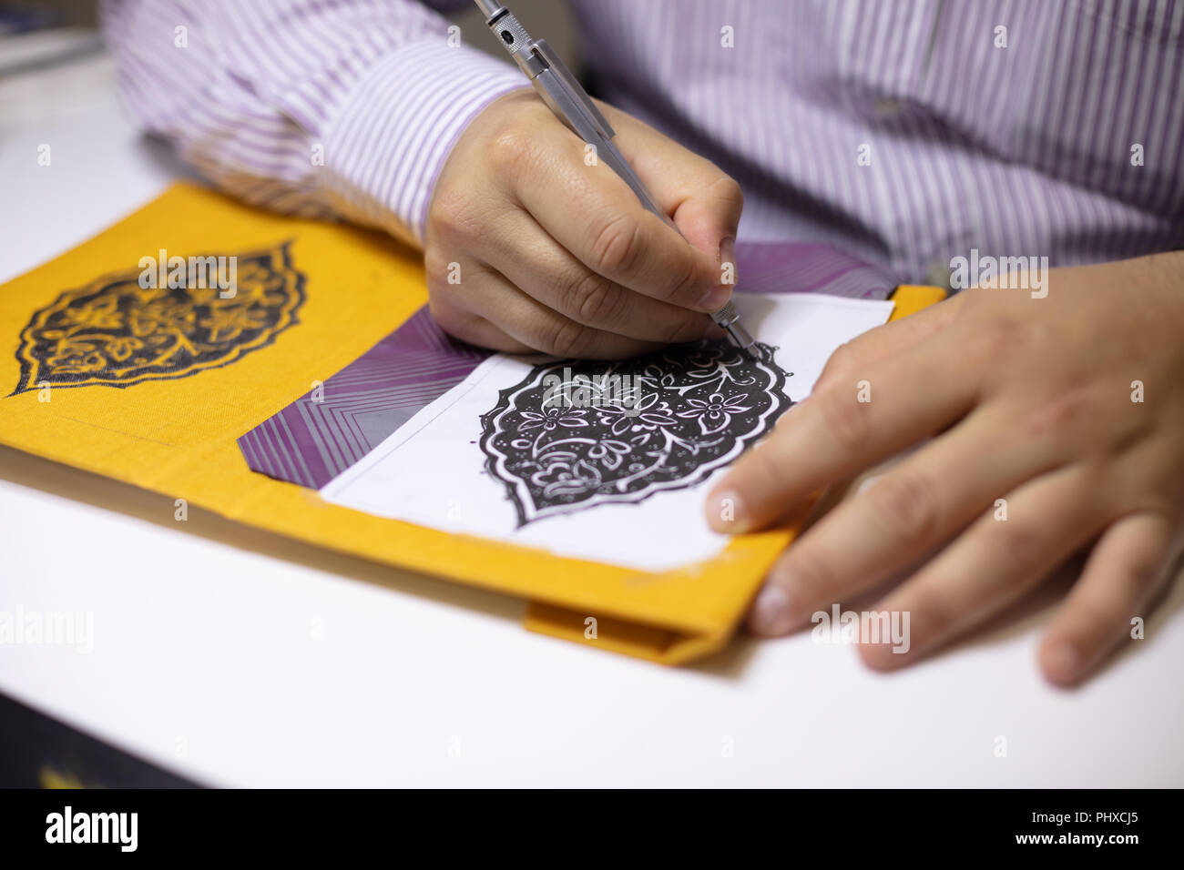 Libro binder mano ilustrando portadas de libros en su taller de patrones  caligráficos en su mesa de trabajo en una vista de primer plano Fotografía  de stock - Alamy
