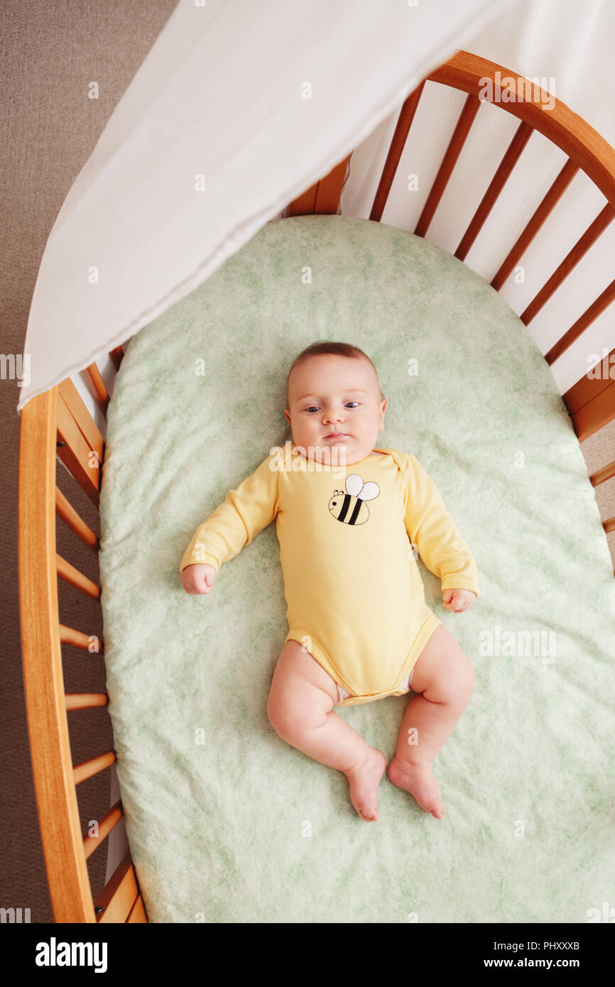 Retrato de lindo gracioso caucásicos blancos adorable pequeño bebé recién  nacido en amarillo onesie acostado en el pesebre solos cerca de la ventana,  estilo de vida, la vida real franco vie Fotografía