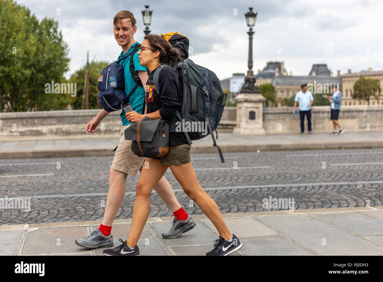 asignación canción Samuel Hombre Mujer sonriendo junto a él cuando caminan por una acera de París  llevando mochilas Fotografía de stock - Alamy
