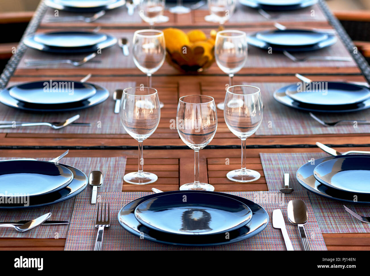 Ajuste de la tabla vacía con copas de vino, platos y cubertería servido en una mesa de madera. Cerca de vajilla, platos, ningún pueblo. Preparación de la cena Foto de stock