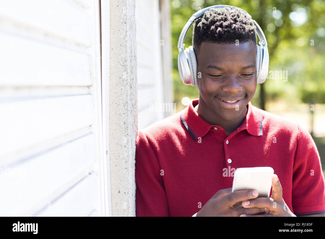 Adolescente al aire libre streaming de música desde teléfonos móviles a auriculares inalámbricos Foto de stock