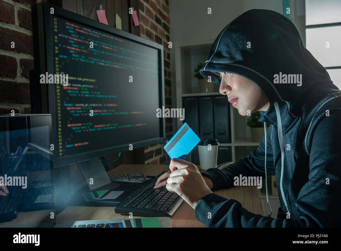 Bastante hacker listo para crímenes de internet. sonreír y celebración de tarjeta de crédito robada por otros. Foto de stock