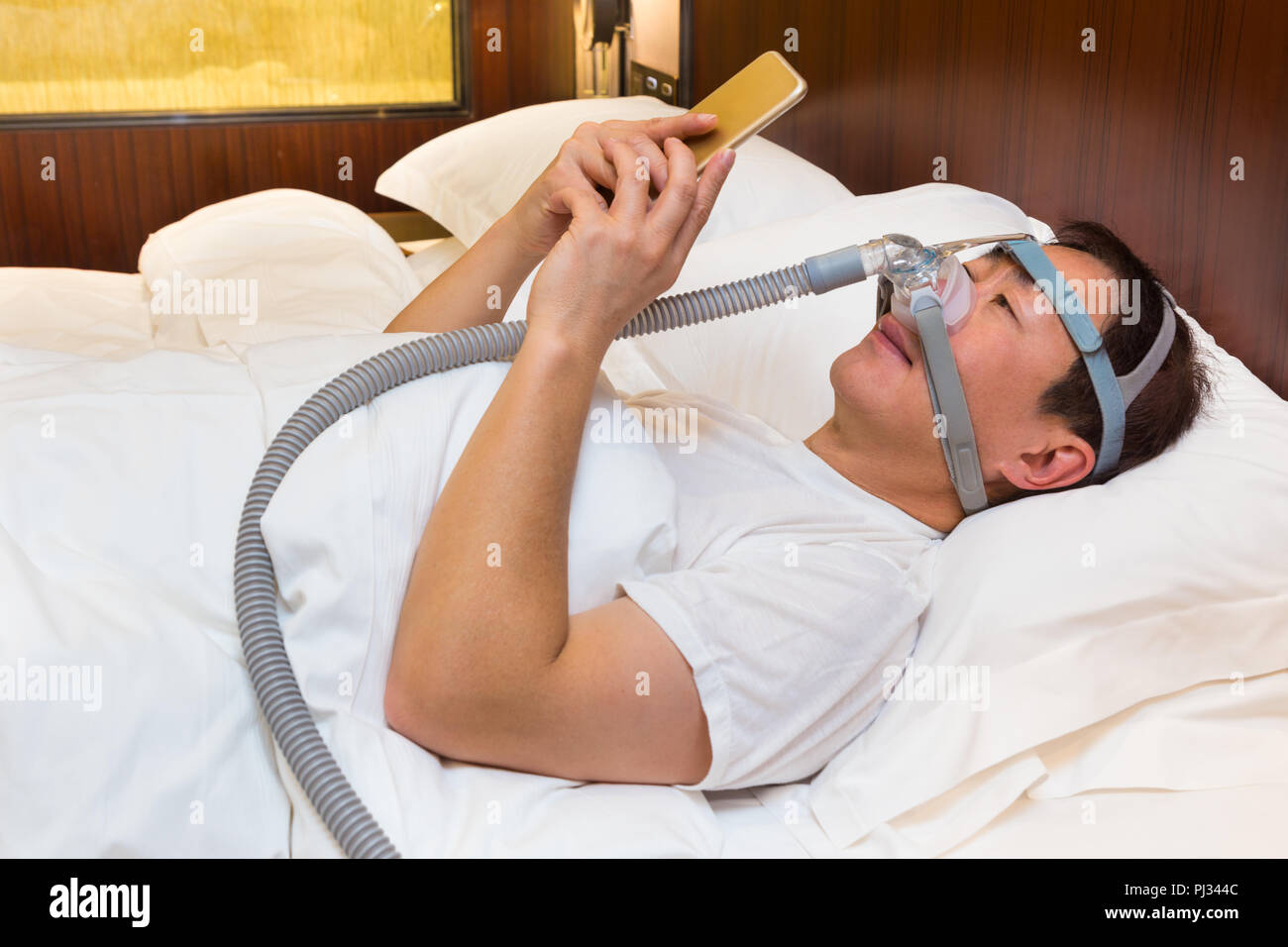 Hombre Asiático Con La Apnea Del Sueño Usando La Máquina De CPAP, Usando La  Máscara De Arnés Que Conecta Al Tubo De Aire, Enfoque Selectivo En El  Hombre Máscara Y El Arnés