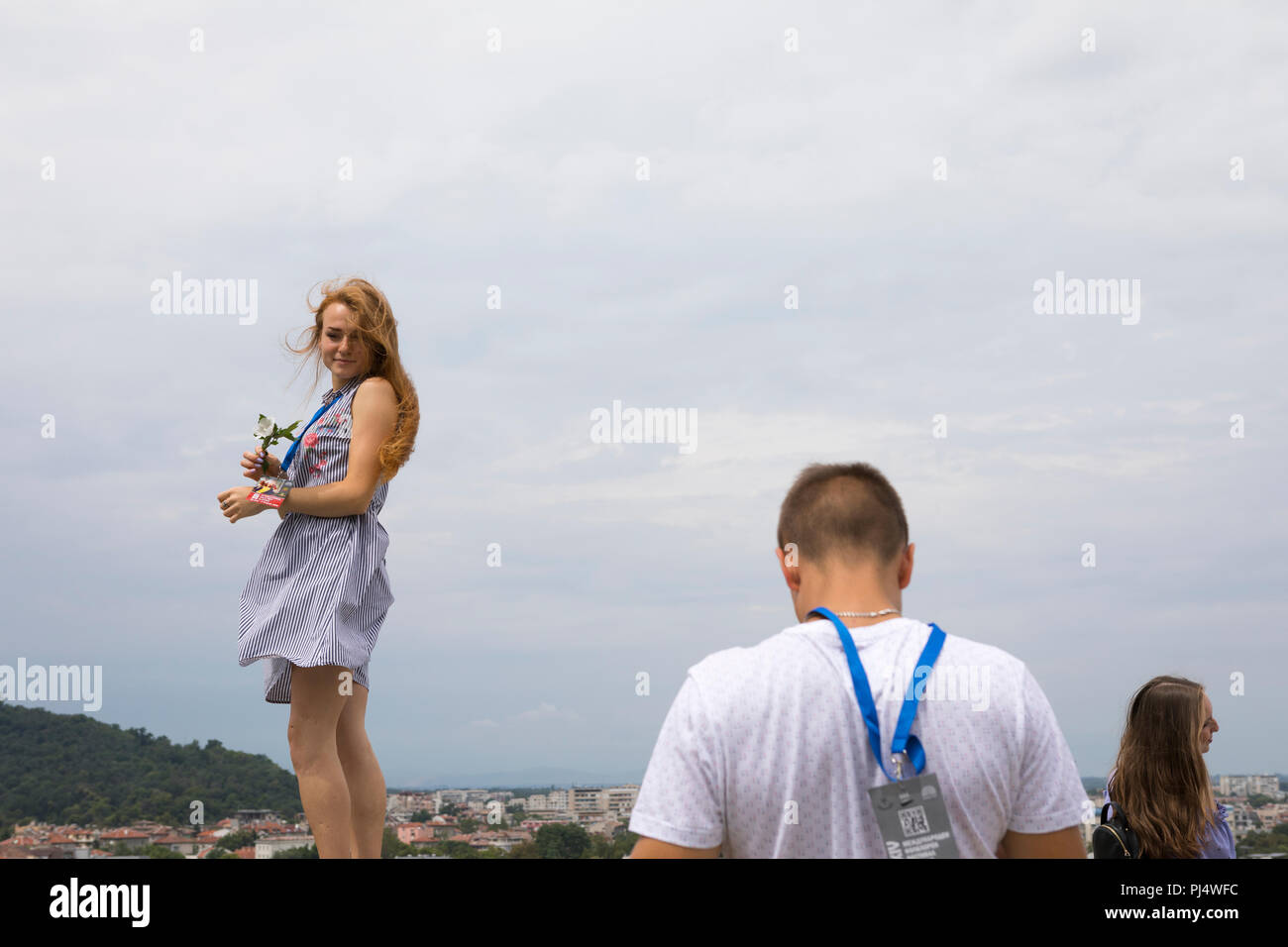 Chico haciendo fotos de su novia posando con una flor en la pared de Nebet Tepe, historia romana y sitio de Tracia en la ciudad de Plovdiv, Bulgaria Foto de stock