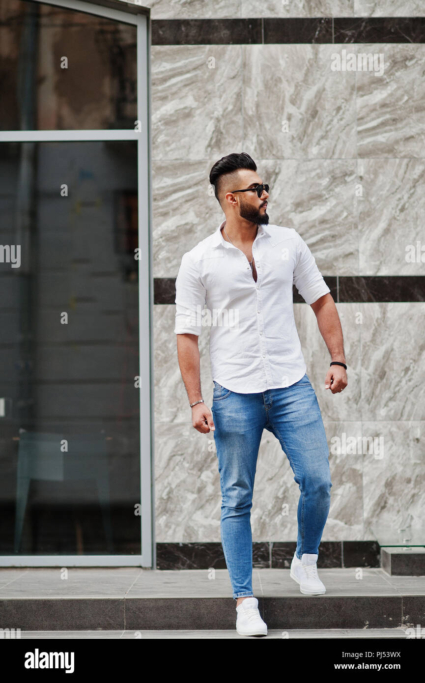 Elegante tall arabian hombre modelo en camisa blanca, vaqueros y gafas de  sol que plantean en la calle de la ciudad. Barba atractivo chico árabe  Fotografía de stock - Alamy