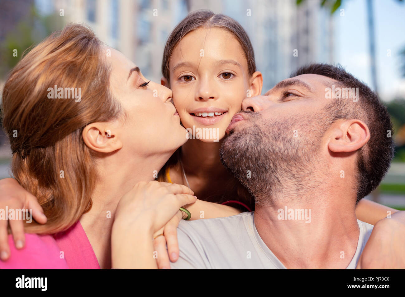 Padres amorosos gozosa besar a su joven hija Foto de stock