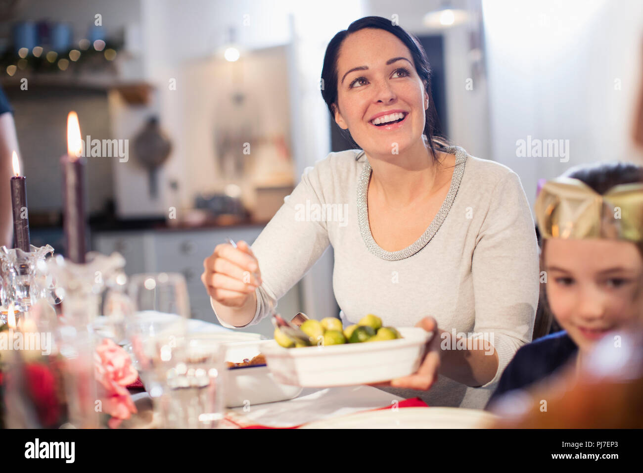 Mujer sonriente sirviendo a las coles de Bruselas en la mesa de cena de Navidad Foto de stock