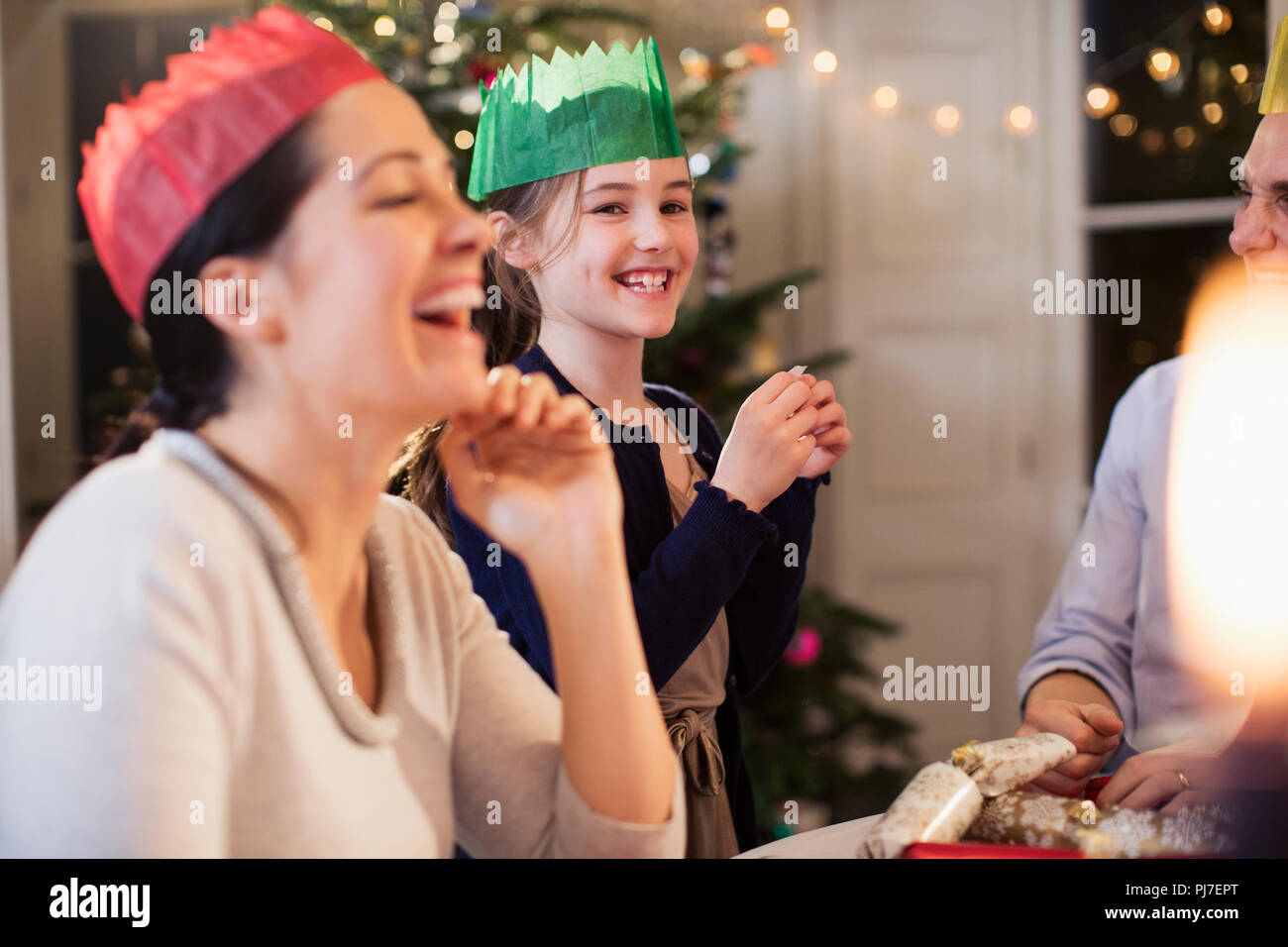 Familia Feliz en coronas de papel riendo en la cena de Navidad Foto de stock