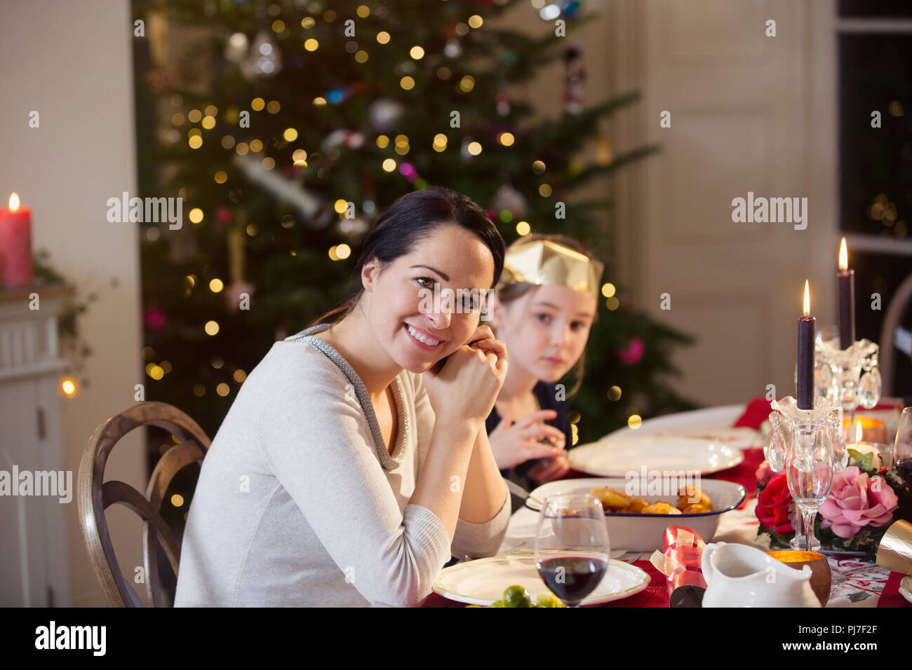 Retrato sonriente, madre e hija disfrutando de la cena de Navidad con velas Foto de stock