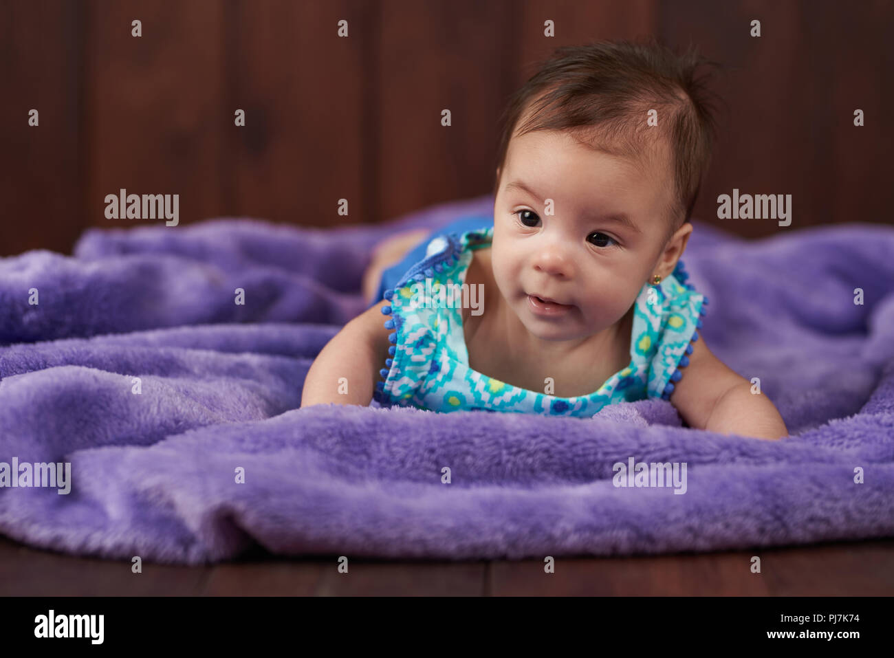 Retrato de cute little baby girl sobre fondo de madera oscura. Foto de stock