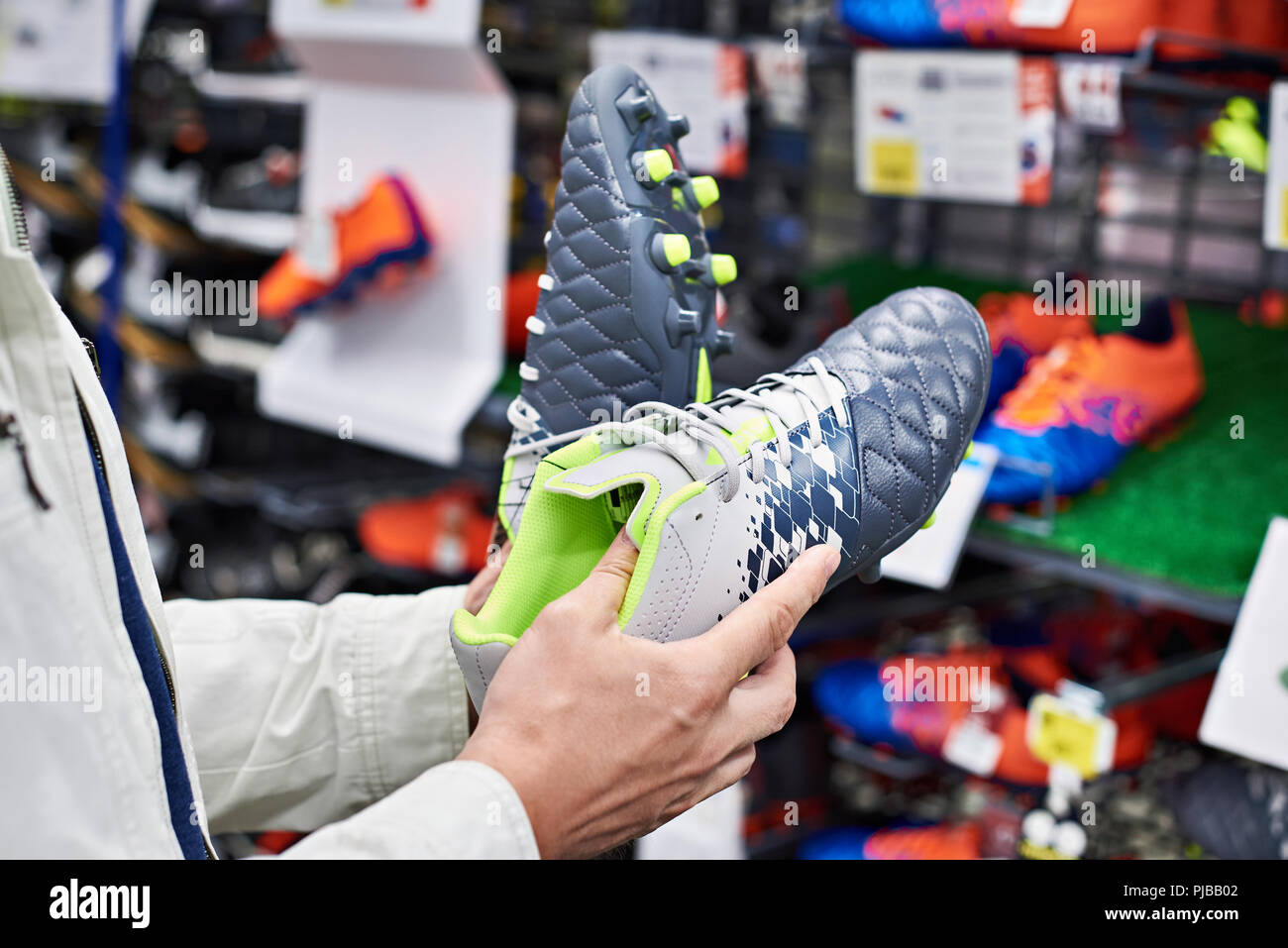 Manos de un hombre con botas de fútbol en una tienda de deportes Foto de stock