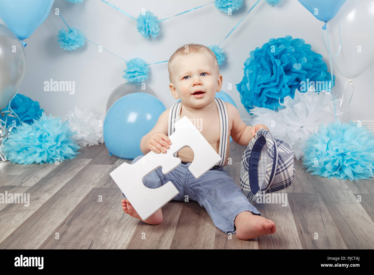 Lindo y adorable bebé caucásico en corona azul celebrando su primer  cumpleaños en casa. Niño niño niño niño pequeño sentado en silla alta  mirando el cupcake dess Fotografía de stock - Alamy