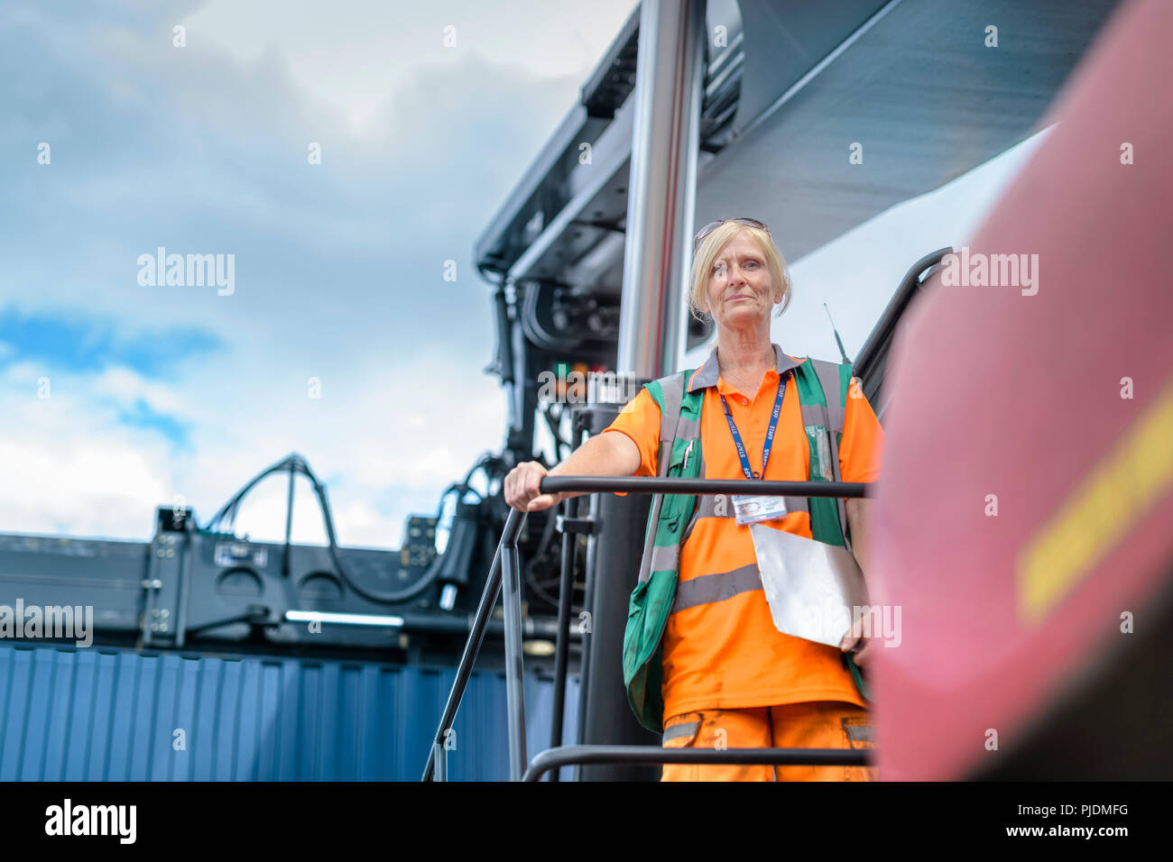 Retrato de mujer con operador de elevación de contenedores en el puerto del contenedor de envío Foto de stock
