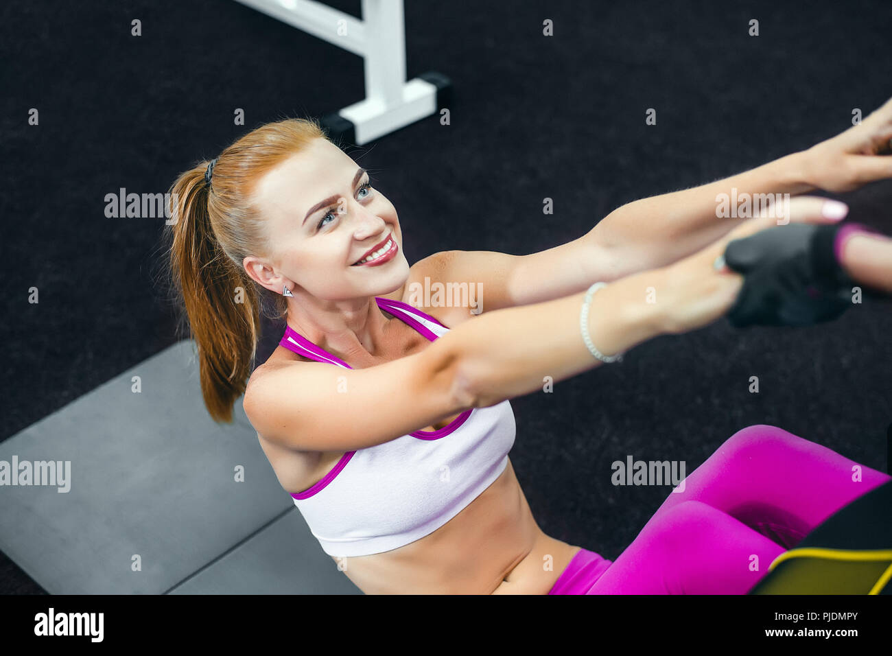 Mujer realizando sentarse ups en el gimnasio y sonriente Foto de stock