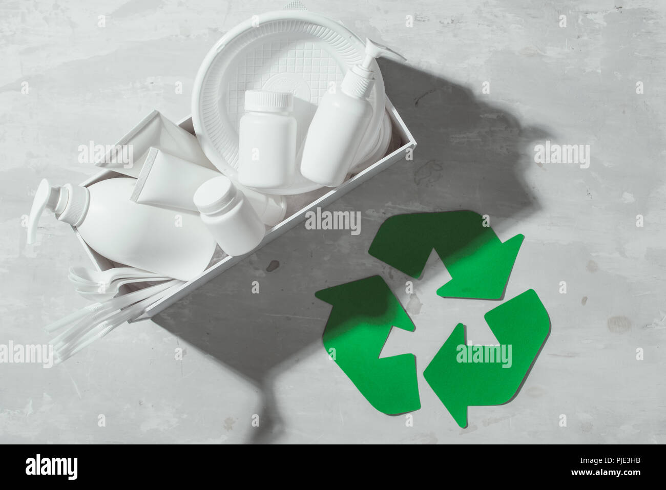 Símbolo ecológico de reciclado de residuos con la basura en el fondo de la tabla de piedra vista superior Foto de stock