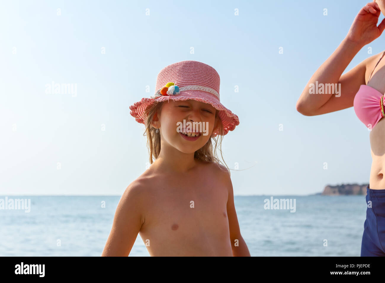 Niño feliz chica en verano hat es con su mamá relajándose en la playa de Sunny. Foto de stock