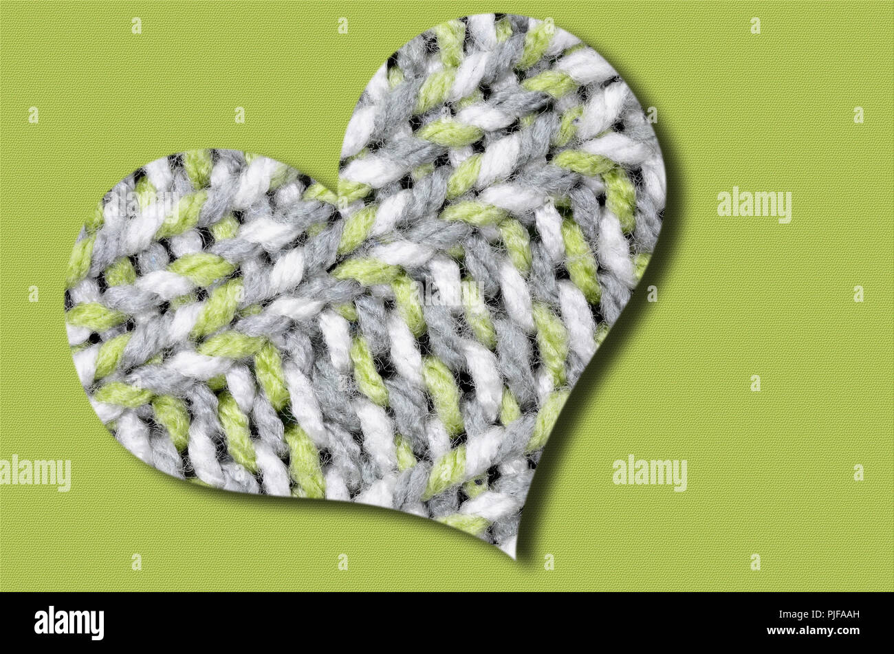 Tejida de corazón, luz verde, gris y blanco, aislado sobre fondo verde claro Foto de stock