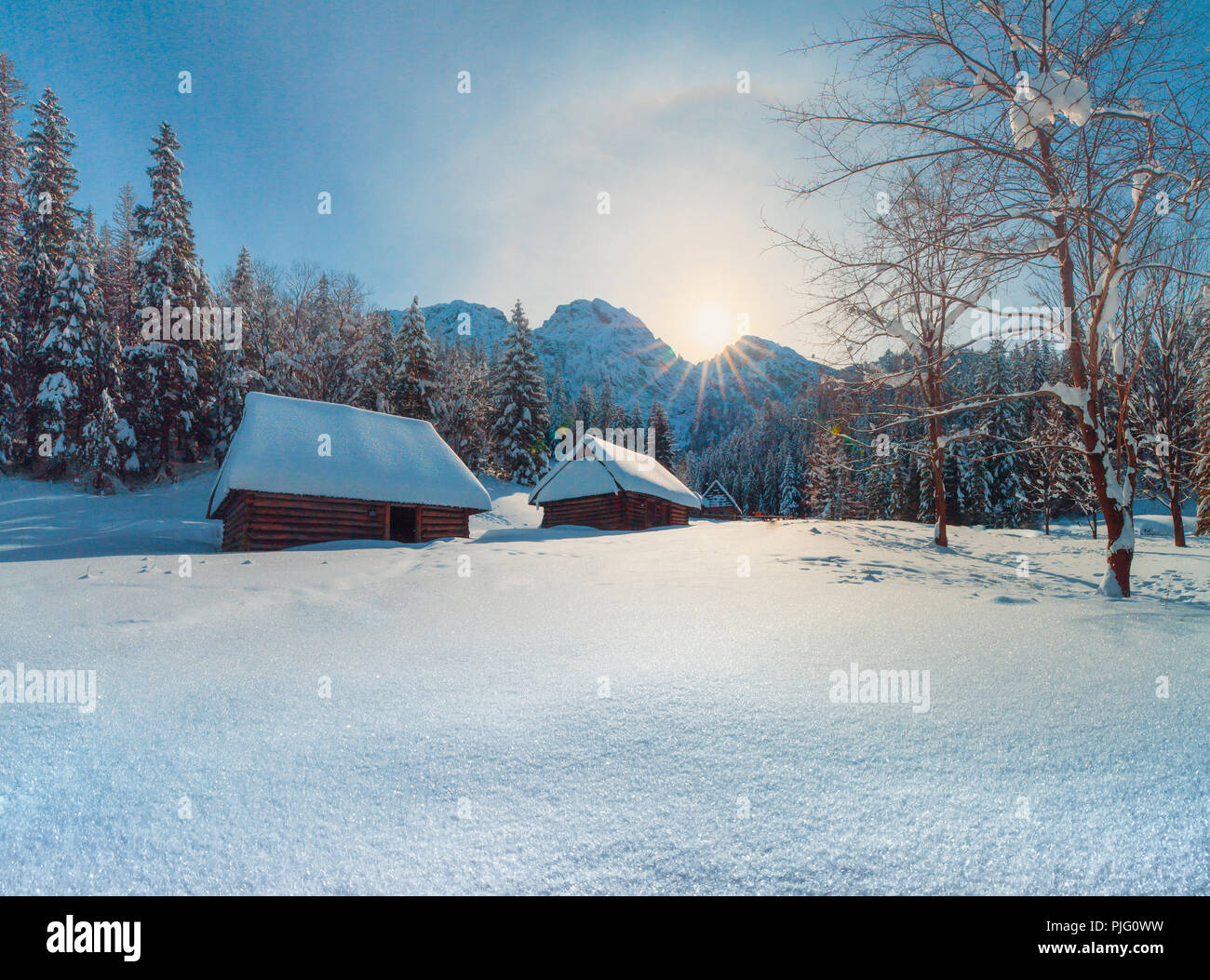 Paisaje invernal. Montañas nevadas colinas con casas antiguas. Sol sobre las montañas de pico. Fondo de Navidad. Foto de stock