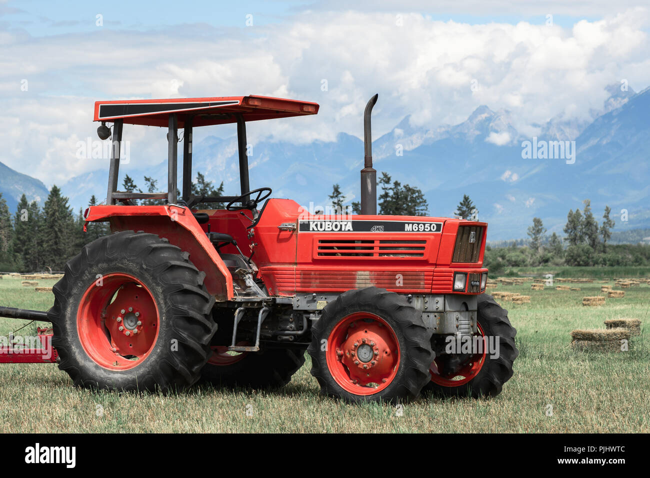 Brisco,BC / Canadá - 11 de julio de 2018:Granja tractor en un campo de heno en las Rocosas Canadienses. Foto de stock