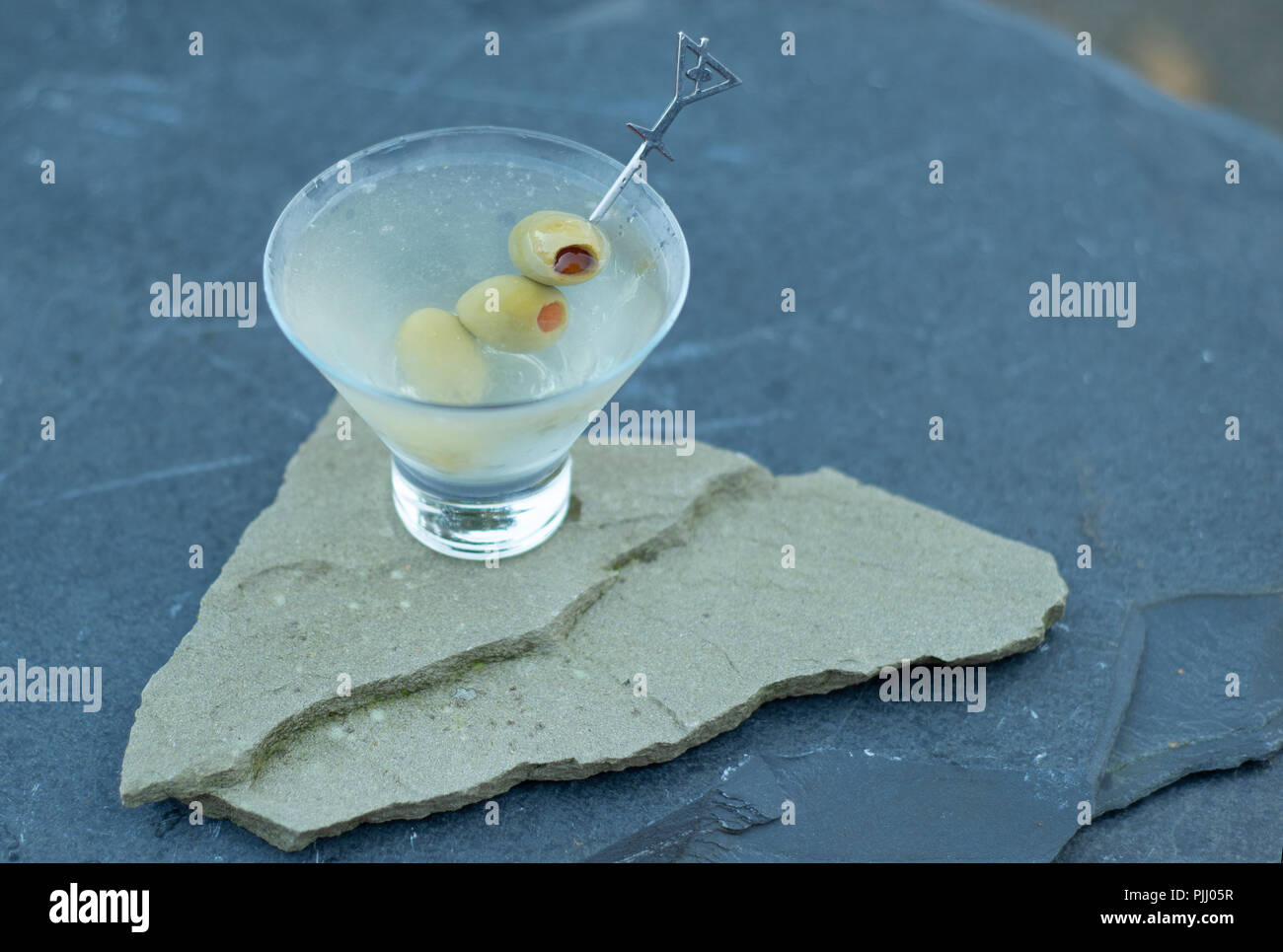 Disfruta fría y refrescante Gin Dirty Martini, agitado, sin mezclar, en una elegante copa de martini, durante un partido de traspatio con familiares y amigos. Foto de stock