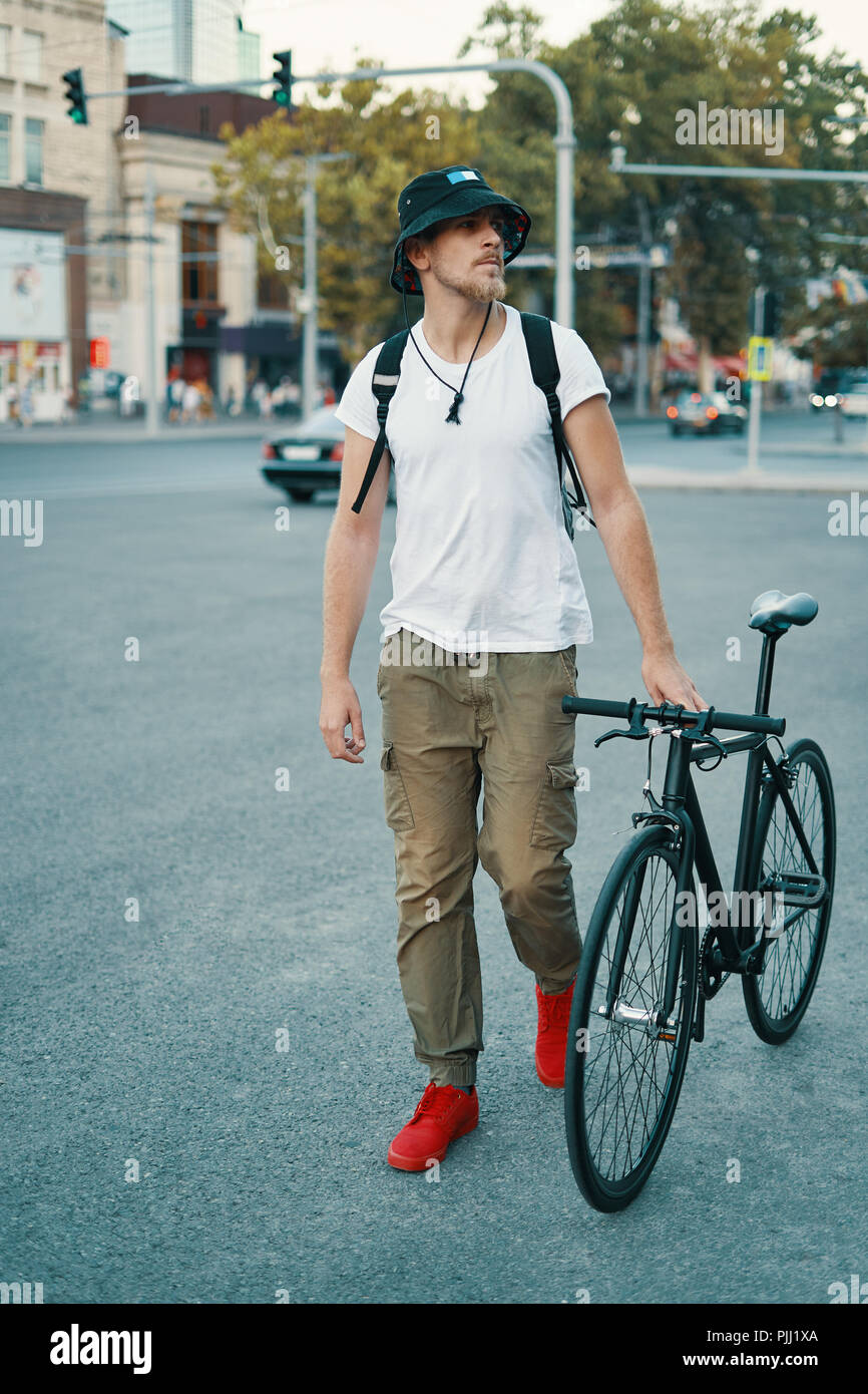 Elegante Hombre con bicicleta para ir a trabajar en la calle. Retrato de  jóvenes varones en ropa casual con mochila caminando por las calles de la  ciudad con elegantes bicicleta. Rojo Fotografía