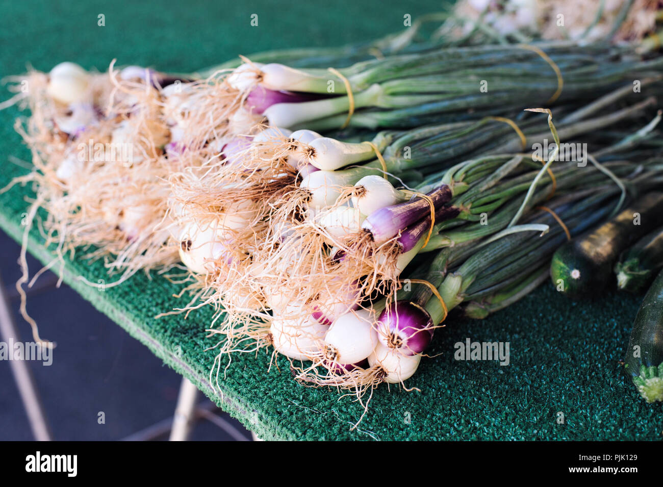 Manojo de cebollas verdes reunidos junto a un establo en el mercado de granjeros Foto de stock