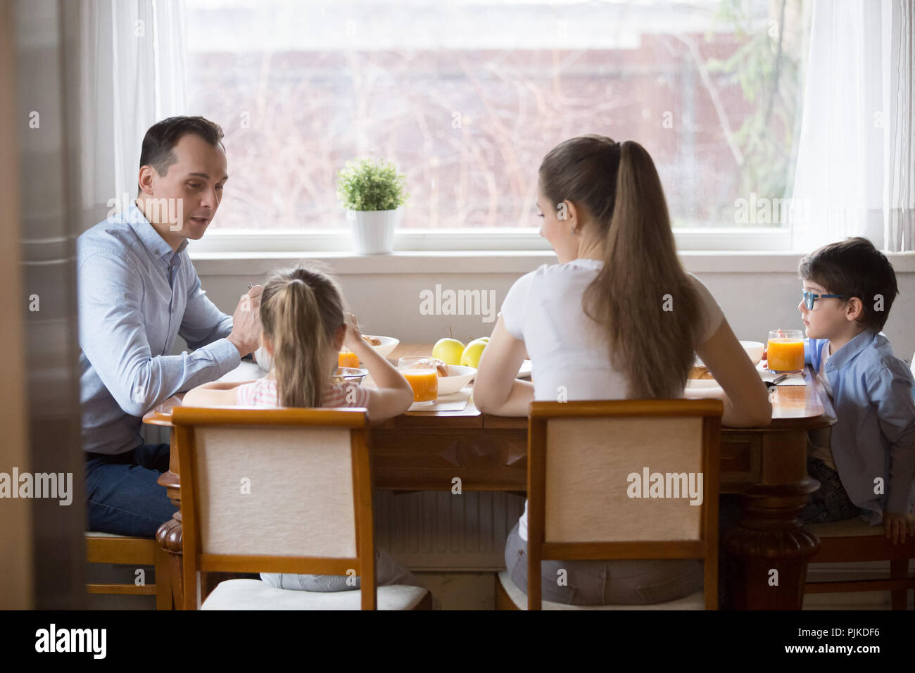 Las familias con niños jóvenes disfrutan de un desayuno saludable en casa Foto de stock