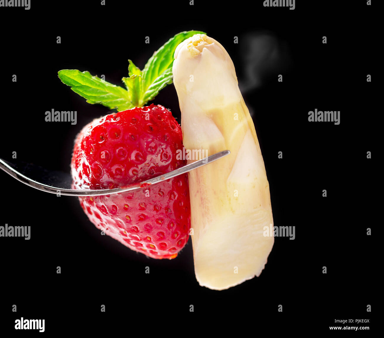 Los espárragos blancos, espárragos punta con fresa en la horquilla guarnecida con menta Foto de stock